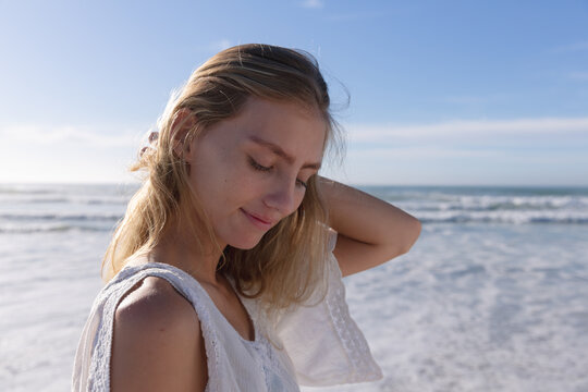 Smiling caucasian woman standing with eyes closed at the beach