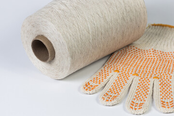 Close-up of spool with cotton thread and construction glove on white background