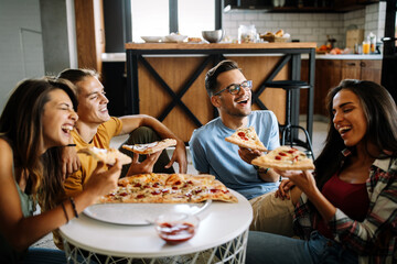 Cheerful multiracial friends having fun and eating pizza at home