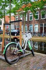 Fototapeta na wymiar Bicycle parked near the canal in Delft street with old houses. Delft, Netherlands