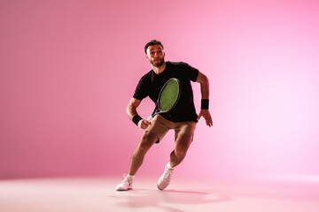 Fototapeta na wymiar Young caucasian man playing tennis isolated on pink studio background, action and motion concept