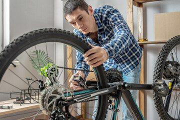 Fototapeta na wymiar Man fixing a mountain bike in a workshop. Concept of preparation for the new season, repair and maintenance