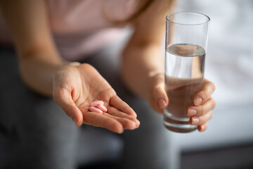 Coronavirus prevention and treatment concept. Closeup view of young woman taking pills with water at home