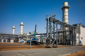Kzylorda province, Kazakhstan. Modern gas power plant in desert. Pipelines, smoke stacks, industrial buildings and mobile crane. Blue sky background.