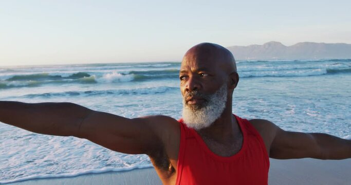 Senior african american man practising yoga at the beach