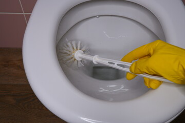 A man washes the toilet bowl with a brush. Interior.