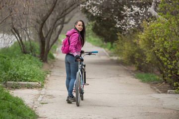a sporty girl is standing on the road with a bicycle, going for a ride