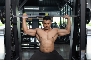 Fototapeta na wymiar A Man Pumping Up Muscles with Weight Lifting Machine in a Gym