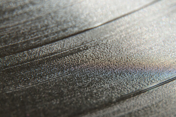 A vinyl record with dust motes and hairs on the macro. Selective focus