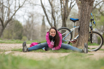 Naklejka na ściany i meble a sporty girl rides a bicycle, she sits on the twine by a tree and smiles. funny portrait