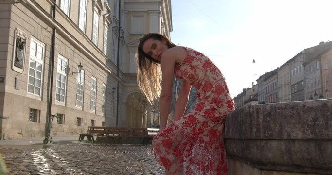 Gorgeous female model with brown hair, wearing stylish maxi dress posing outdoors during summer morning. Concept of relaxation, beauty and lifestyle. 