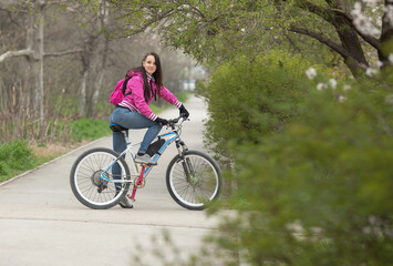 Fototapeta na wymiar sporty girl rides a bicycle on a pedestrian path, spring landscape.