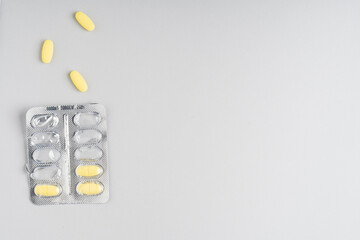 Yellow pills on gray background, top view. Different medicines, tablets, medicine capsules. Medicine concept, background. Text place