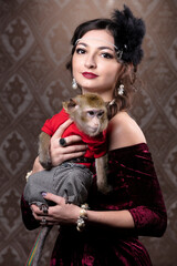 Retro female portrait in the style of 20s or 30s. A gorgeous lady is holding a little monkey.