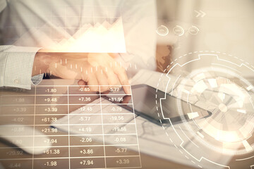 Double exposure of man's hands holding and using a digital device and forex graph drawing. Financial market concept.