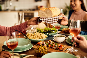 Close-up of unrecognizable people passing bread during a meal at dining table.