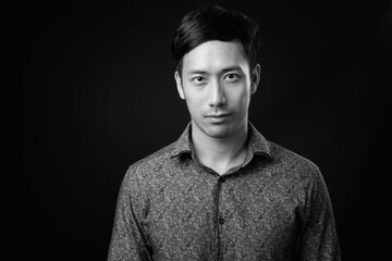 Young handsome Asian businessman against black background