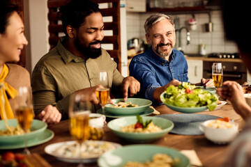 Fototapeta na wymiar Happy mid adult man enjoying in lunch with his friends in dining room.