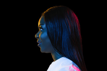 Fototapeta premium African young woman's portrait on dark studio background in neon. Concept of human emotions, facial expression, youth, sales, ad.