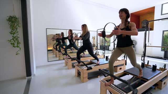 Company of women doing lunges on pilates reformer
