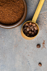 Gold coffee scoop with coffee beans  and  ground coffee on concrete background.Copy space