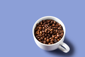 White coffee cup with coffee beans on violet backgrund. Copy space