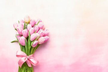 Pink tulips bouquet decorated with ribbon on a pink background. Mothers Day, Valentines Day, bachelorette concept.