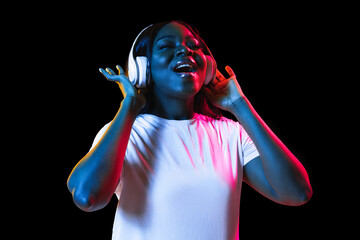 African young woman's portrait on dark studio background in neon. Concept of human emotions, facial expression, youth, sales, ad.