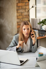 Businesswoman in office. Beautiful woman talking on phone at work..