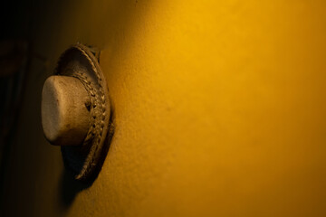 Sombrero de gaucho colgado en una pared amarilla, símbolo de tradición