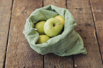 Zero waste shopping. Fresh apples in eco cotton bag on rustic wood. Eco sustainable lifestyle