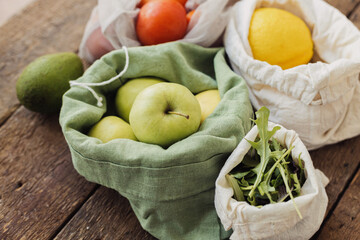Plastic free eco grocery delivery. Fresh fruits and vegetables in eco cotton bags on rustic wood