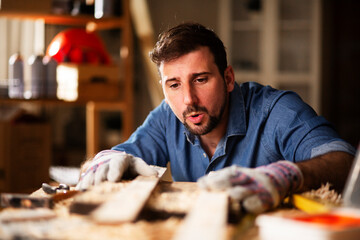 Young male carpenter working in workshop. Carpenter working on wood craft at workshop..