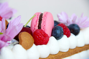biscuit cake with cream, macarons and red berries