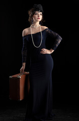 A beautiful girl dressed in the style of the 20-30s of the last century with a cigar and a suitcase...