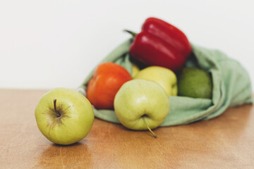 Zero waste shopping. Fresh apples, avocado, tomatoes, pepper in cotton bag on wooden table