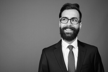 Young handsome bearded Persian businessman against gray background