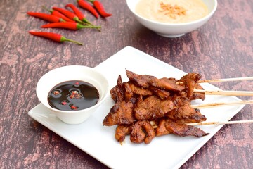 Sate Ayam or Chicken satay or Chicken skewers. Indonesian food. Served with peanut sauce, thick soy sauce and chili 