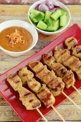 Indonesian chicken satay or Sate Ayam. Served with peanut sauce and pickles cucumber 