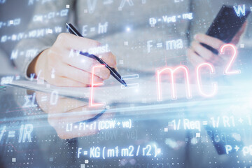 Double exposure of formulas sketch hologram and woman holding and using a mobile device. Education concept.