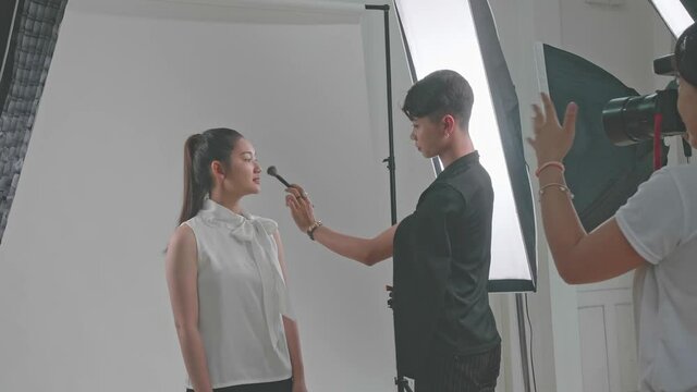 Backstage Of The Photo Shoot: Make-Up Artist Applies Makeup On Beautiful Asian Model For A Photographer
