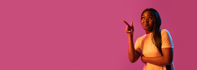 African young woman's portrait on pink studio background in neon. Concept of human emotions, facial...