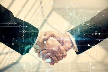 Double exposure of data theme hologram and handshake of two men. Partnership in IT industry concept.