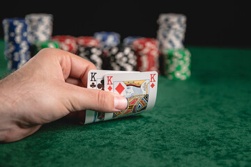 Chips and cards for poker in hand on green table