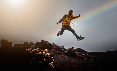 Man jump through the gap over the mountain rocks at sunset