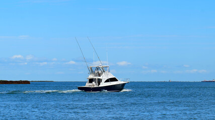 Broadside view of a beautiful white and black fishing yacht boat sails on the calm blue water on a sunny day.