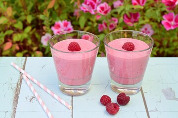 Raspberry smoothies with pink flowers on the background