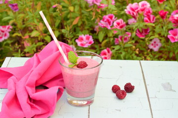 Raspberry smoothies with pink flowers on the background