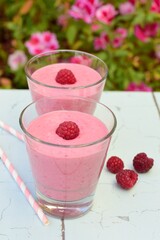 Raspberry smoothies with pink flowers on the background