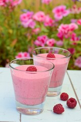 Raspberry smoothies with pink flowers on the background
